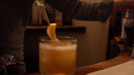 bartender pours penicillin cocktail at bar over ice