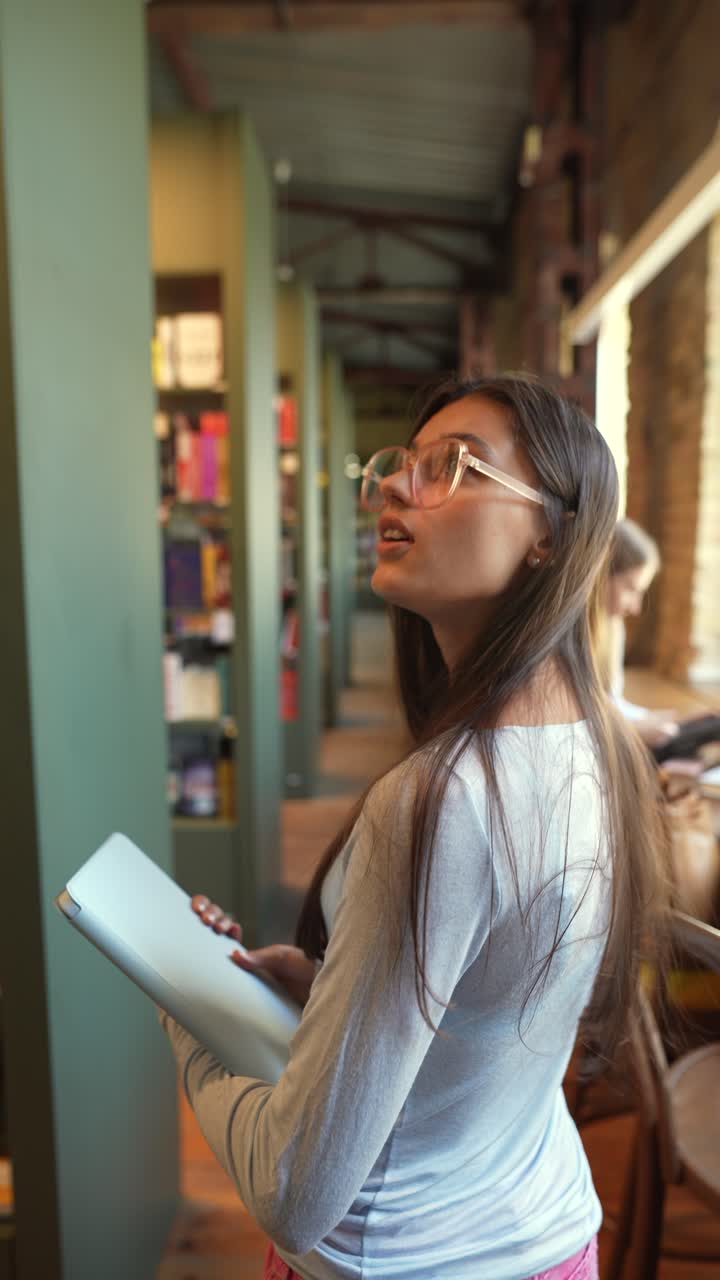 mujer en la biblioteca con una computadora portátil