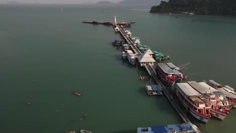 Aerial-reverse-shot-following-the-Bang-Bao-fishing-pier-lined-with-boats-on-the-coast-of-Koh-Chang,-Thailand