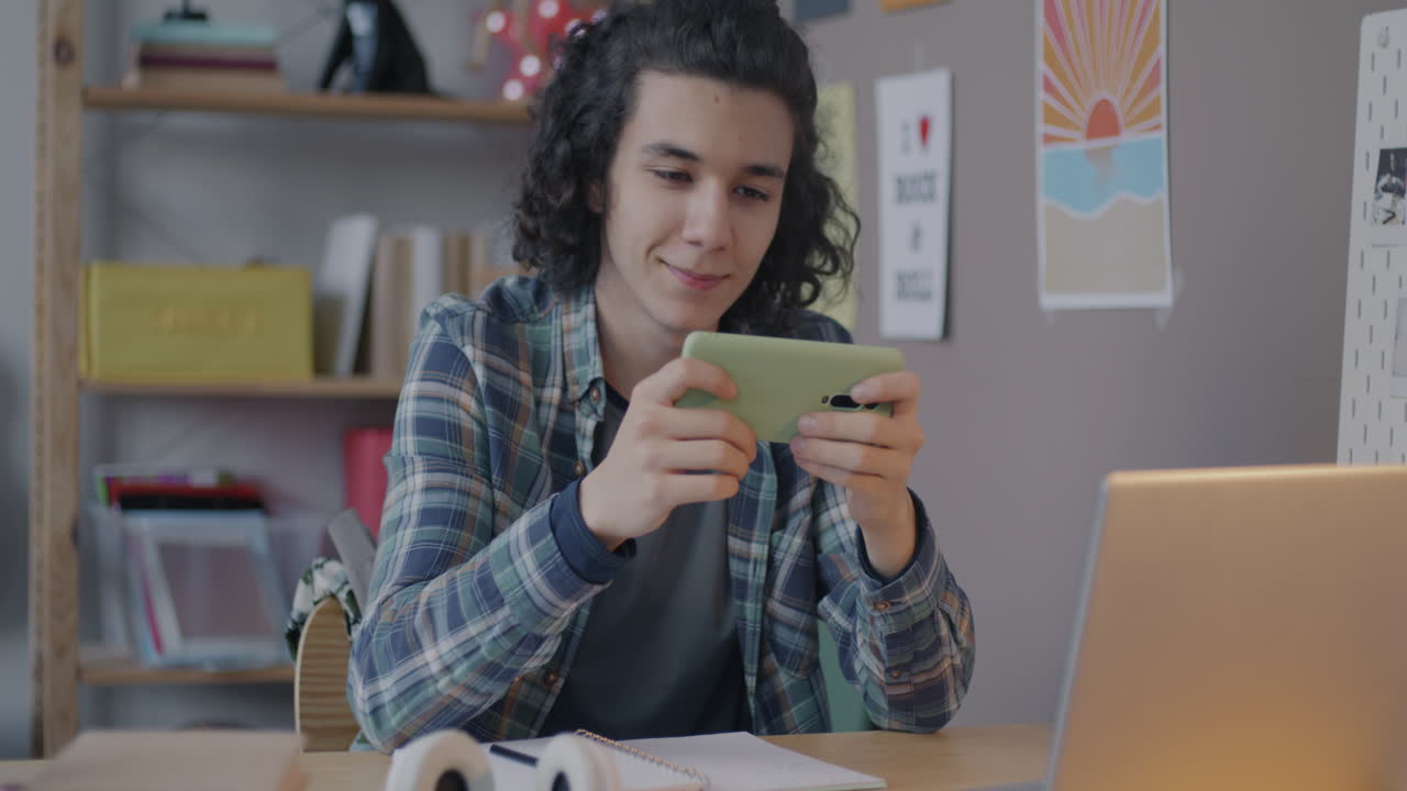 Teenager Playing Mobile Game at Desk
