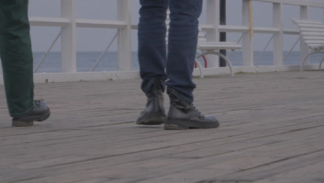 two people walk along a wooden pier