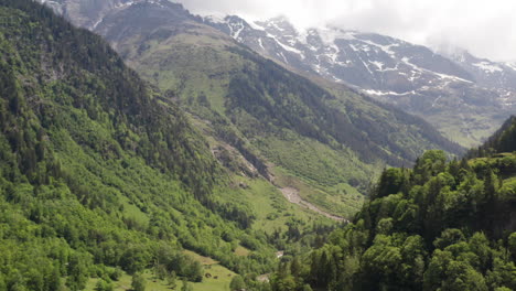 aerial of green valley, tilting up to distant mountains