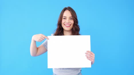 Beautiful-woman-holding-blank-placard-on-blue-background