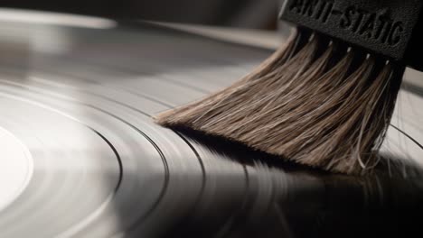mano quitando el polvo de un disco de vinilo con un cepillo antiestático