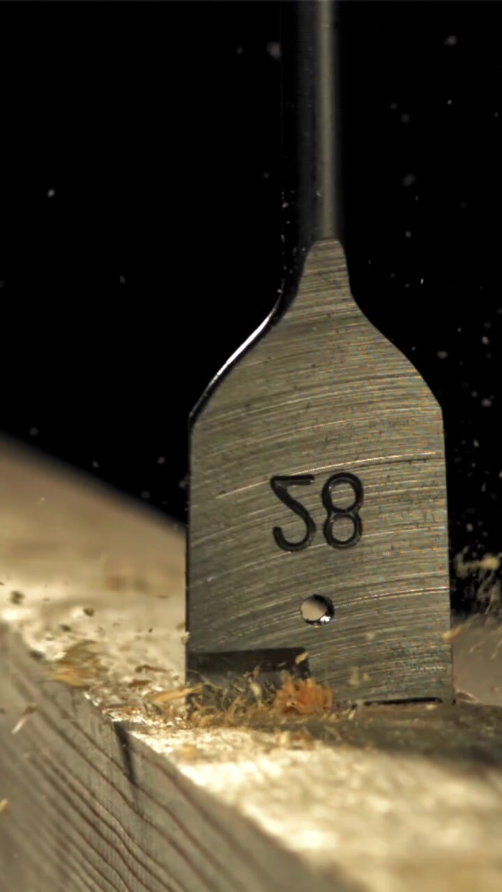 Close-up of a Spade Drill Bit Making a Hole in Wood in Slow Motion