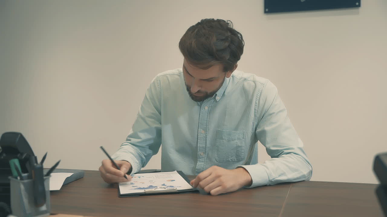Young Business Man Working With Documents With Charts And Graphs