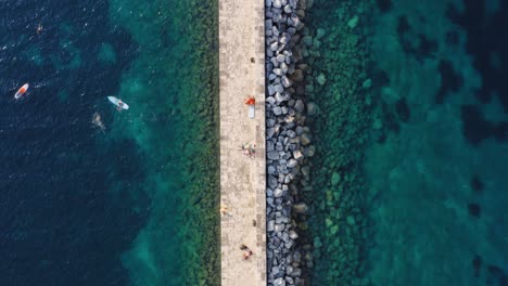 amazing pier on rocky stone mediterranean turquoise coastline, aerial top down