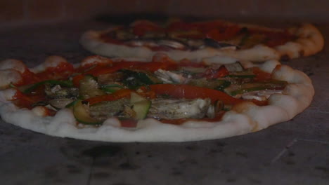 cámara lenta de dos pizzas cocinadas en un horno de leña