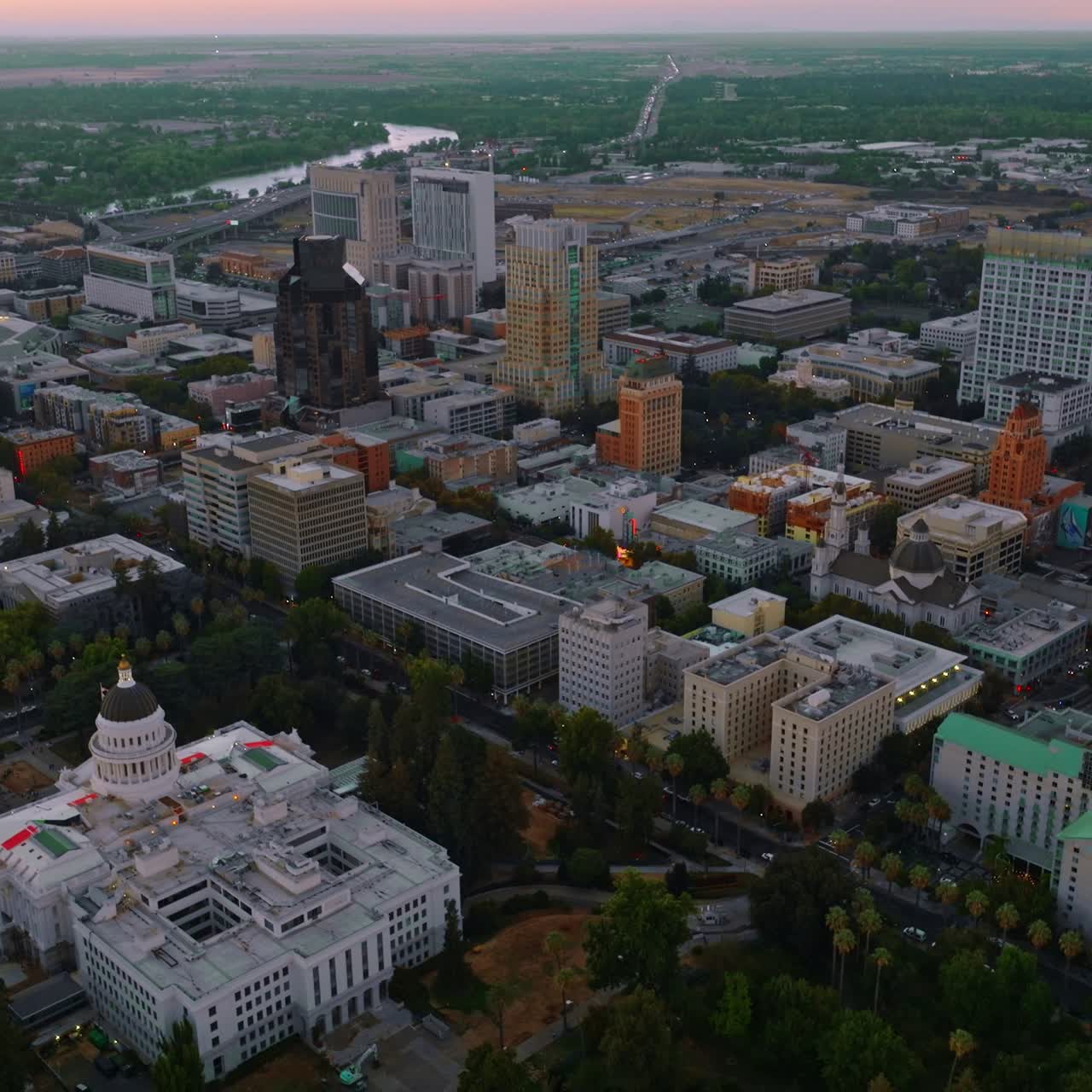 Modern architecture of Sacramento downtown in the evening. River and green landscape at backdrop. Top view