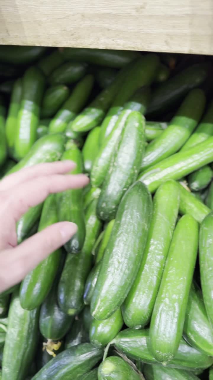 Hand holding cucumber at a grocery store