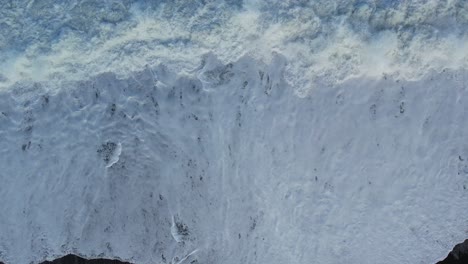 Flying-low-above-white-water-waves-crashing-onto-stony-beach---Canterbury-Bight,-New-Zealand