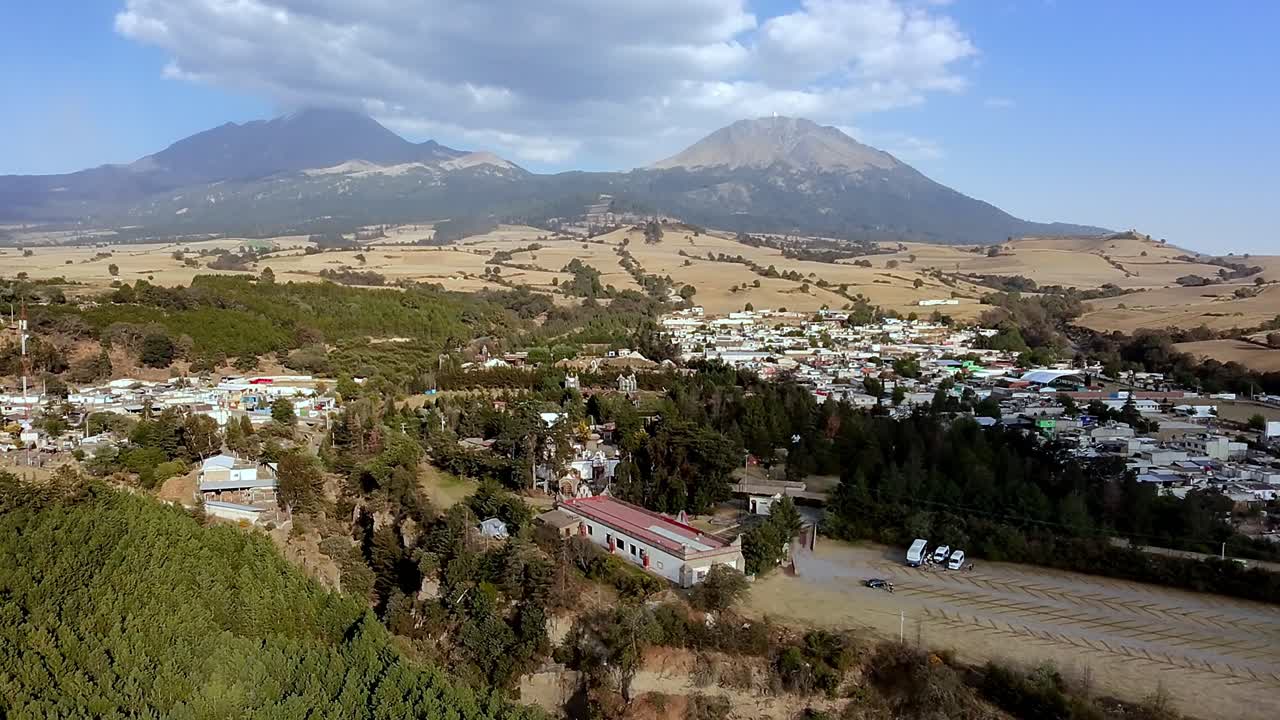 Aerial view of Orizaba Peak, Puebla. Wide shot of the town with farming fields, trees, and Pico de Orizaba volcano in the background