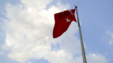 footage of a waving turkish flag on a flag pole and on a blue sky background with some clouds.