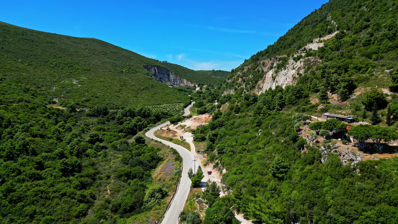 paisaje de montaña en el valle verde, camino entre acantilados, avión no tripulado aéreo vuela lentamente, fondo del horizonte de la luz del día azul