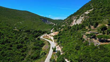 mountain trek landscape in green valley, road between cliffs, aerial drone fly slow, blue daylight skyline background