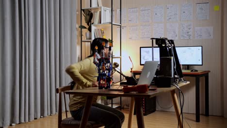 teen asian girl walking to look at the pictures on the wall while working about a cyborg hand at home