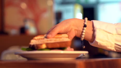 Picking-up-sandwich-in-slow-motion-in-mall-blurry-background-sunset