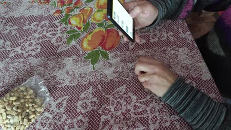 white woman eating peanuts on a table and using cell phone