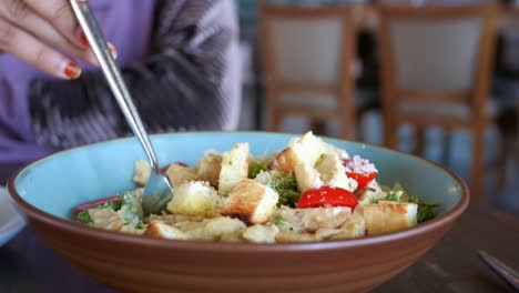una mujer comiendo ensalada de césar.