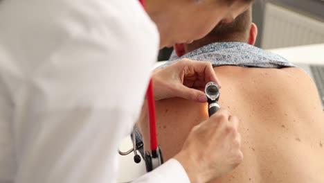 médico examinando los nevos pigmentados de un paciente masculino con dermatoscopio en la clínica película 4k en cámara lenta
