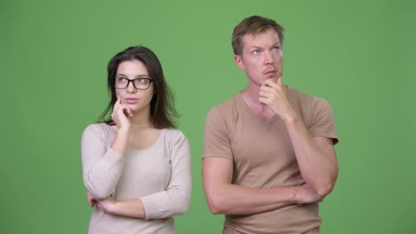 young couple thinking together against green background