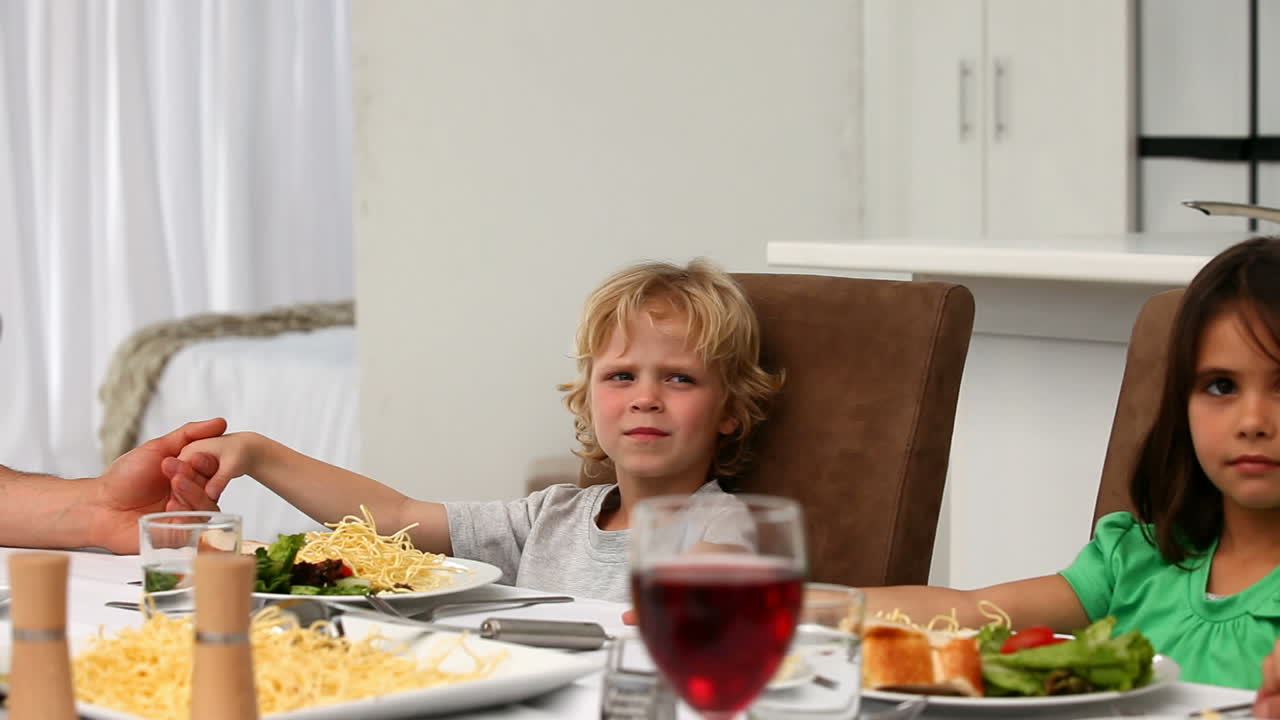 Famiglia carina che prega insieme durante il pranzo