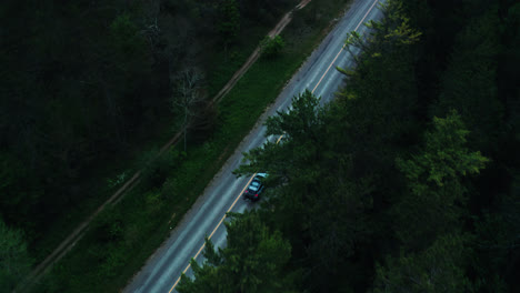 Luftaufnahme-Von-Oben-Nach-Unten-Des-Autos,-Das-Die-Leere-Waldstraße-Hinunterfährt,-Umgeben-Von-Bäumen,-Filmische-Drohnenreise-4k