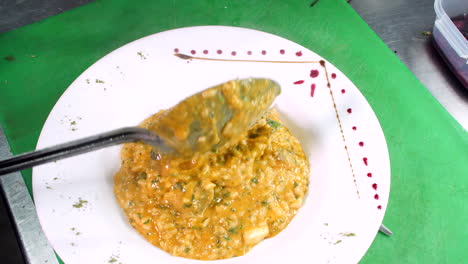 chef decorating seafood risotto in restaurant, close-up, mediterranean