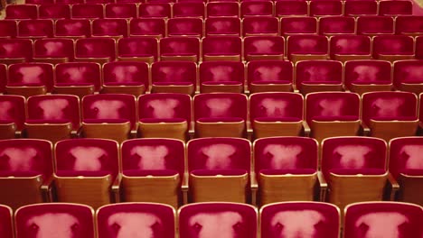 symmetric frontal view from stage on empty red velvet worn armchair seats