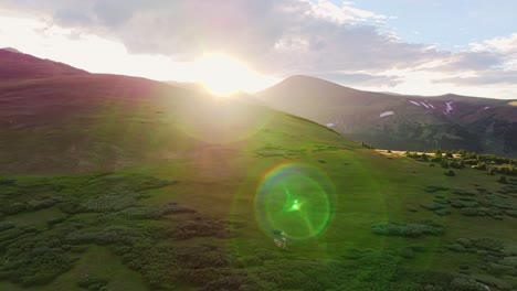 aerial trucking pan across green scrub hillside with beautiful starry sun flare across landscape