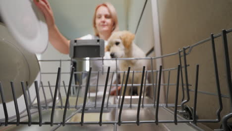 young woman putting dirty plates into the dishwasher