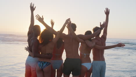 Rear-View-Of-Friends-Watching-Sunset-On-Summer-Beach-Vacation