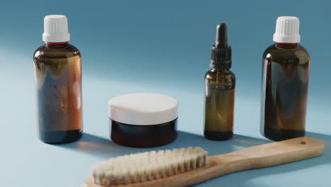 close up of glass bottles, cream tub and brush with copy space on blue background