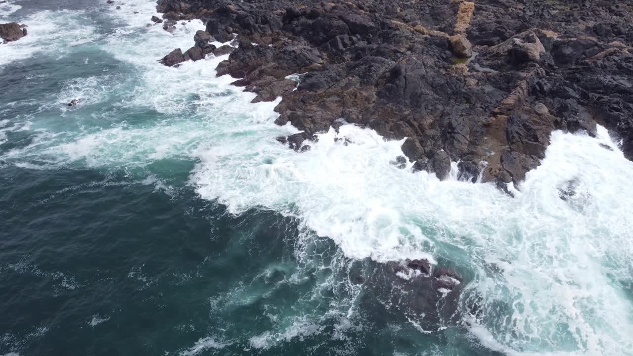 toma aérea de poderosas olas rompiendo en las rocas
