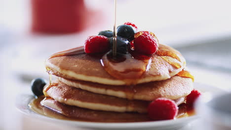 Ahornsirup-Wird-Zum-Pfannkuchentag-Auf-Einen-Stapel-Frisch-Zubereiteter-Pfannkuchen-Oder-Crêpes-Auf-Dem-Tisch-Gegossen