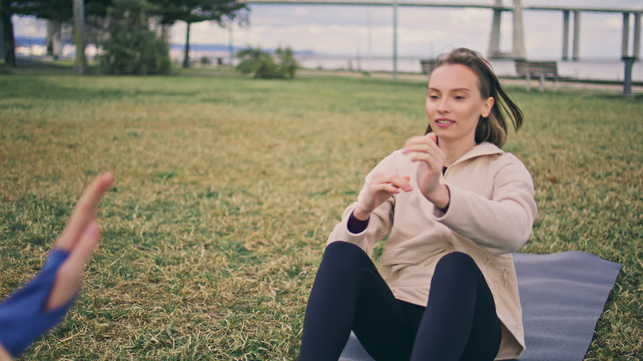 Motivated lady sport training open air. Two women clapping hands abs exercises