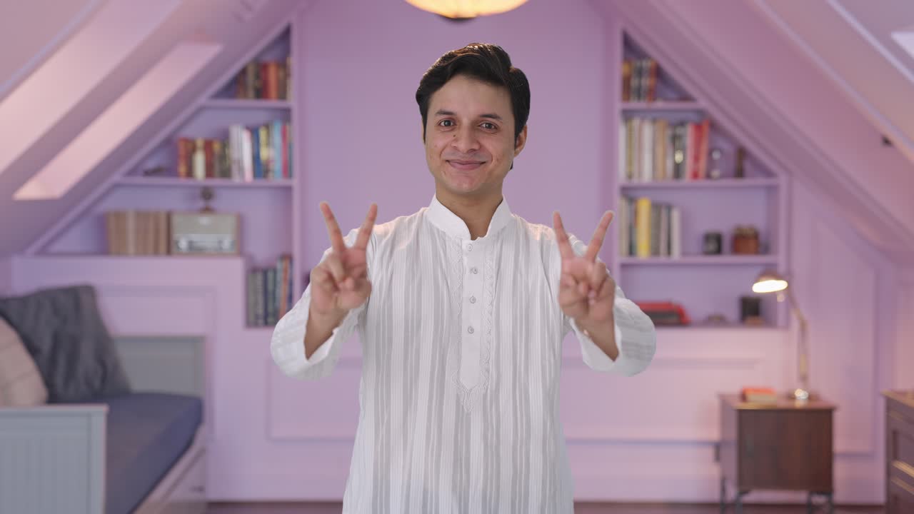 Uomo indiano felice che fa il segno della vittoria