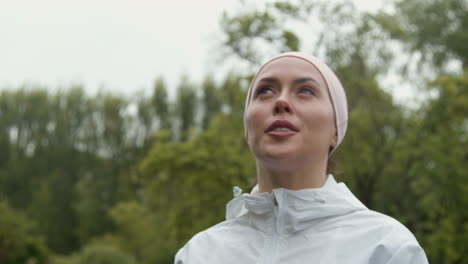 primer plano de una mujer con una cinta para la cabeza haciendo ejercicio manteniéndose en forma corriendo bajo la lluvia 2