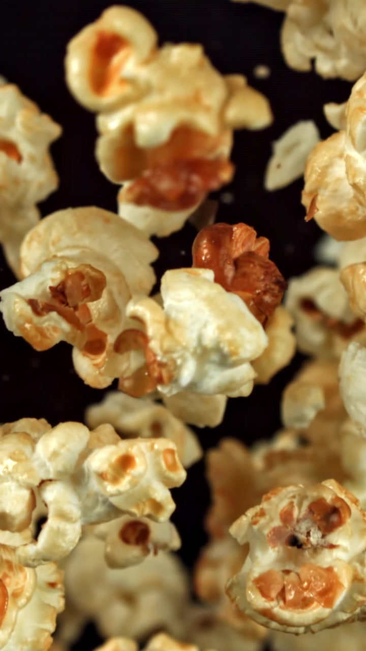 Popcorn al caramello che cadono al rallentatore su sfondo scuro