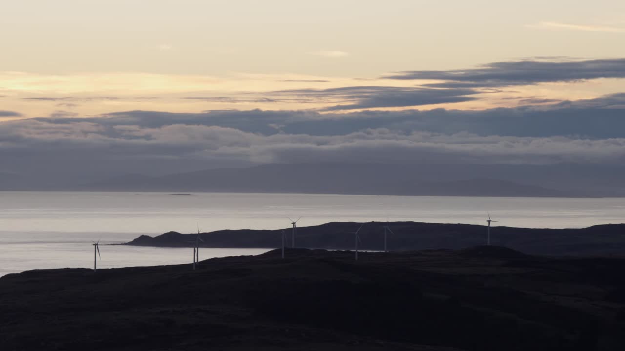 hermoso paisaje de nueva zelanda con océano y montaña distante durante la puesta de sol con molinos de viento