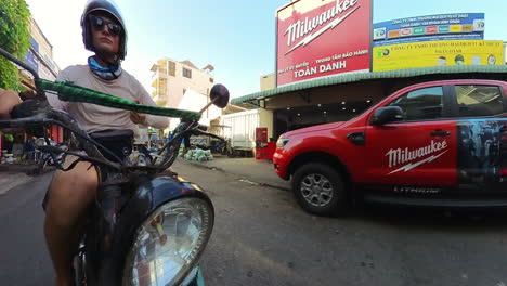 young tourist backpacker traveling in vietnam. motorbike weaving through a busy marketplace. front facing pov action shot.