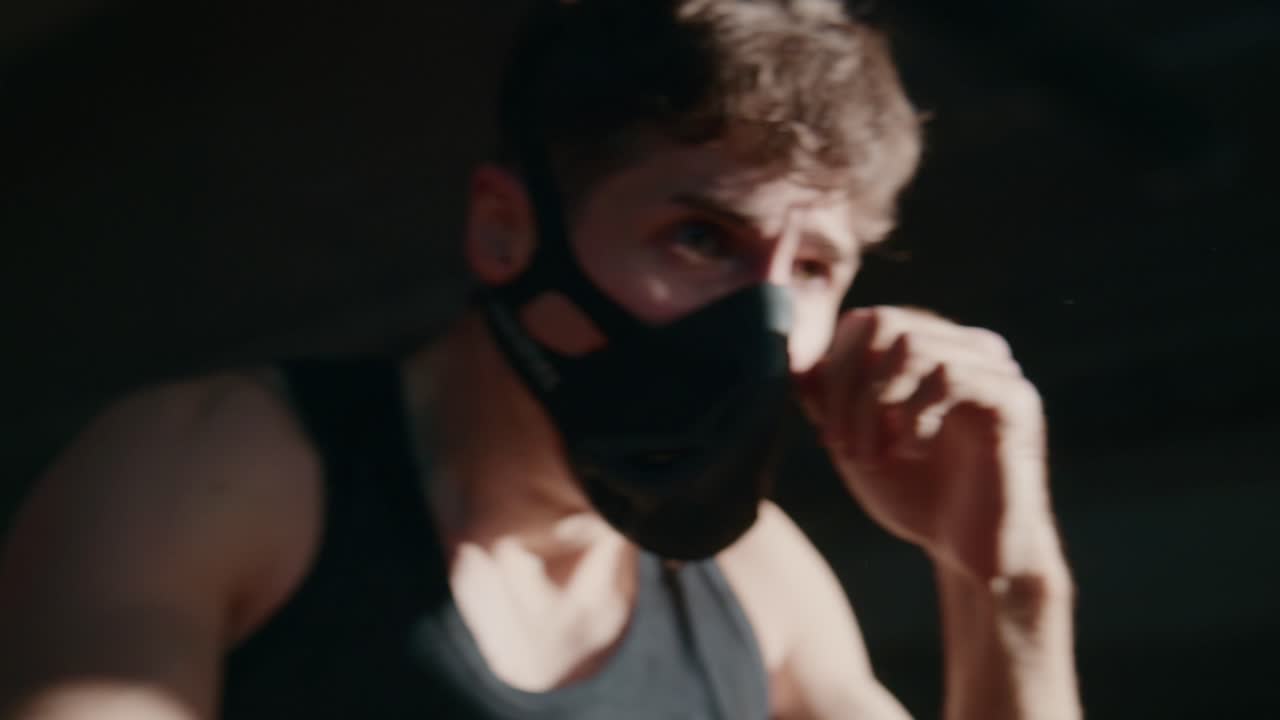 Man in Training Mask Boxing in a Dark Gym