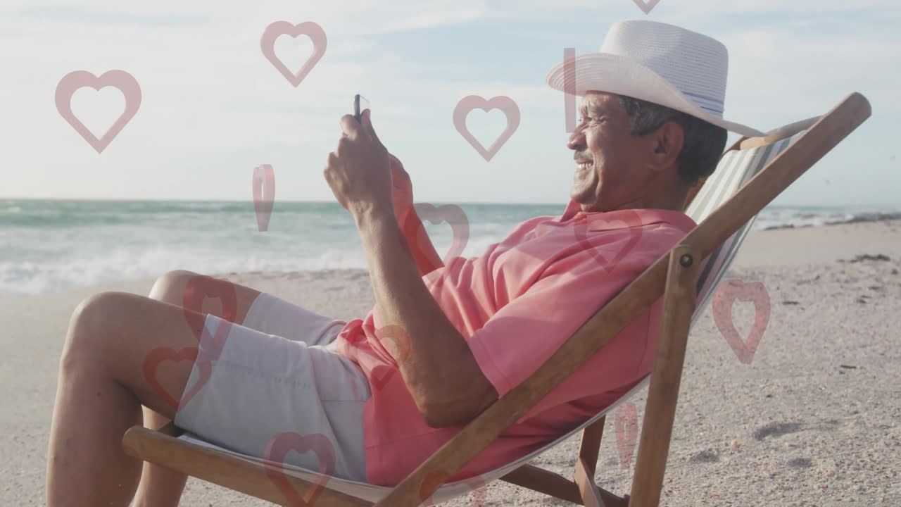 Elderly man relaxing on beach chair, using smartphone with heart animations overlay