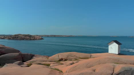 the beautiful scenery of blue calm ocean with big stone on a sunny day in sweden - aerial shot of the stångehuvud light house in lysekil, sweden