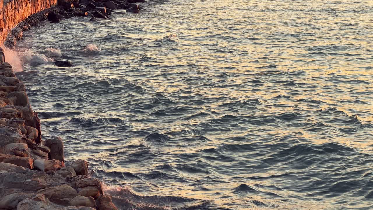 Water clip with waves, sea, ocean, river, lake or lagoon with wind hitting the rocks on the coast.
