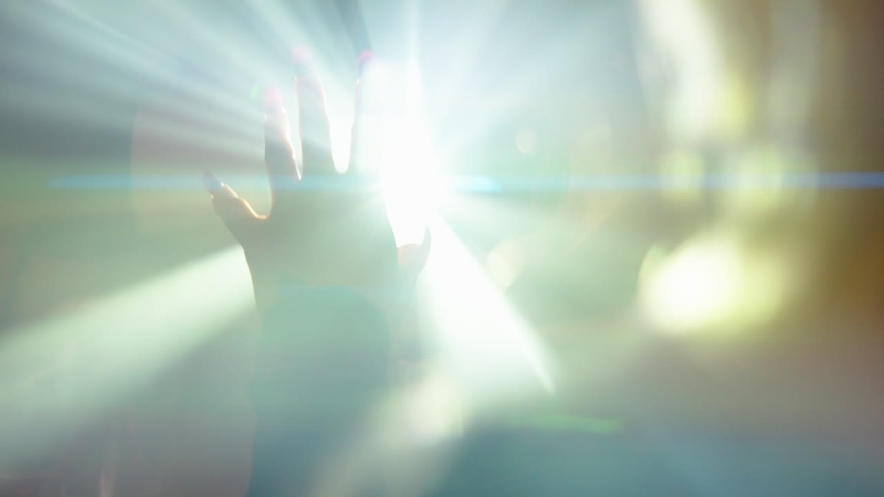 그녀의 손가락을 통과하는 밝은 빛의 광선에 그녀의 손을 잡고 여자