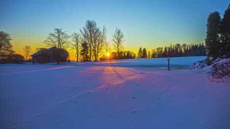 Timelapse-of-scenic-sunrise-across-golden-sky-over-snowy-field
