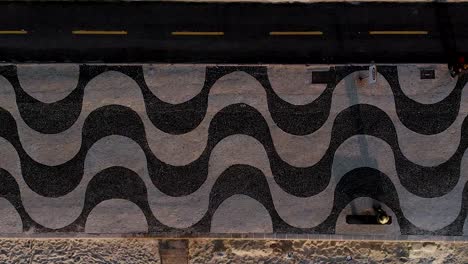 Early-morning-sideways-aerial-panning-showing-the-patterns-in-the-sidewalk-pavement,-bicycle-lane-and-beach-of-Copacabana