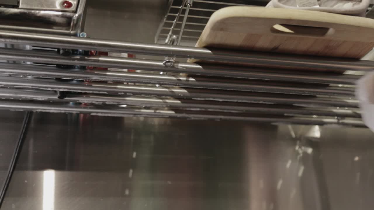 Wiping Off The Soapsuds From The Stainless Steel Sink Rack Drainer With A Dry Clean Cloth - Close Up Shot