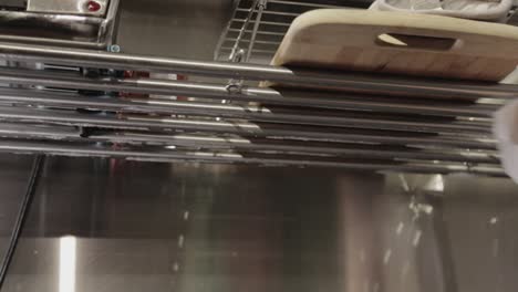 wiping off the soapsuds from the stainless steel sink rack drainer with a dry clean cloth - close up shot